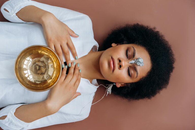 A woman meditates with a Tibetan singing bowl and crystals, promoting wellness and spiritual healing.