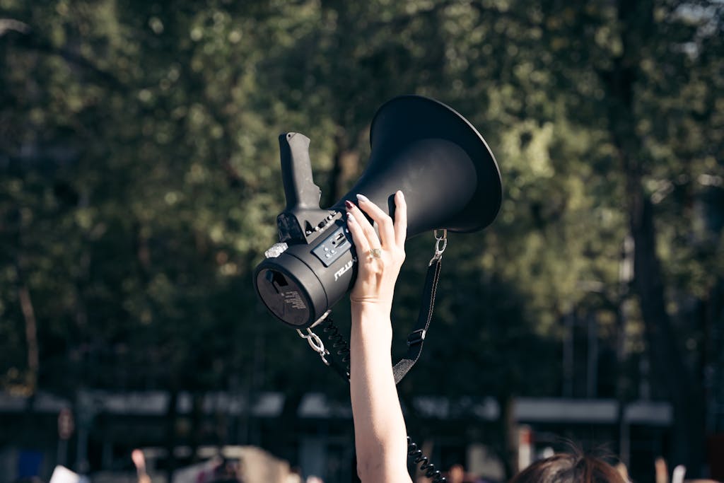 A hand holds a megaphone aloft at a rally in Mexico City, symbolizing protest and activism.