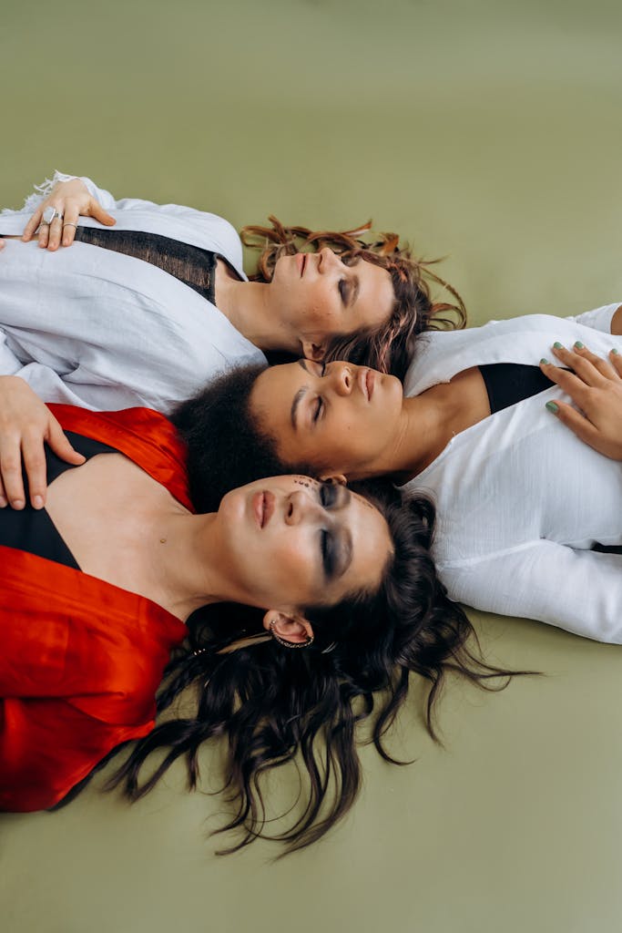 Three diverse women lying down in meditation pose, representing relaxation and unity.